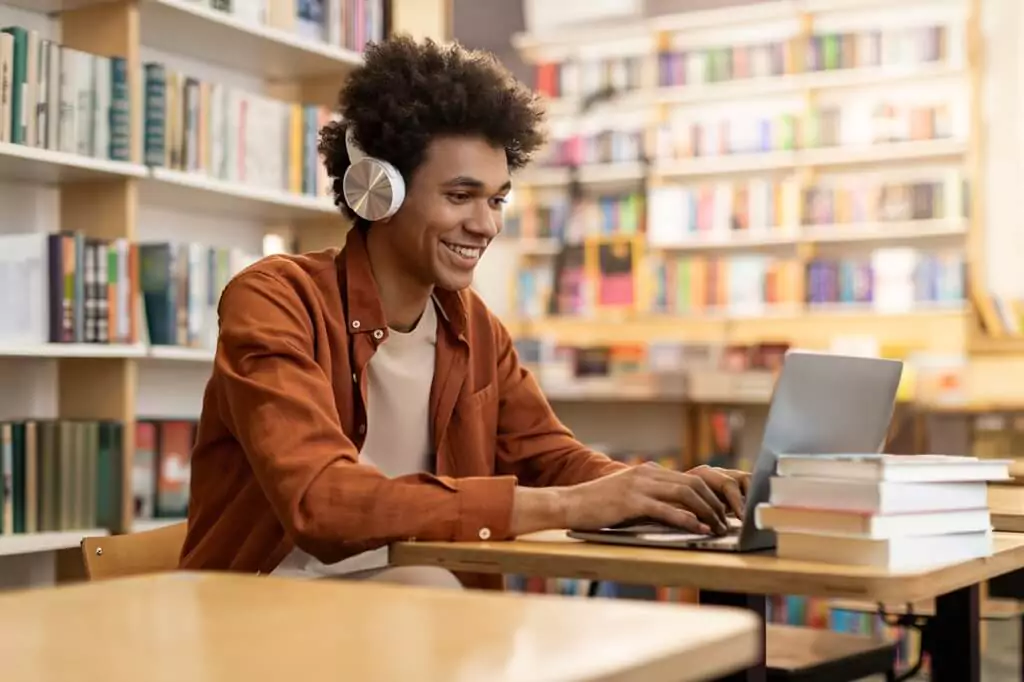 rapaz estudando em biblioteca com computador