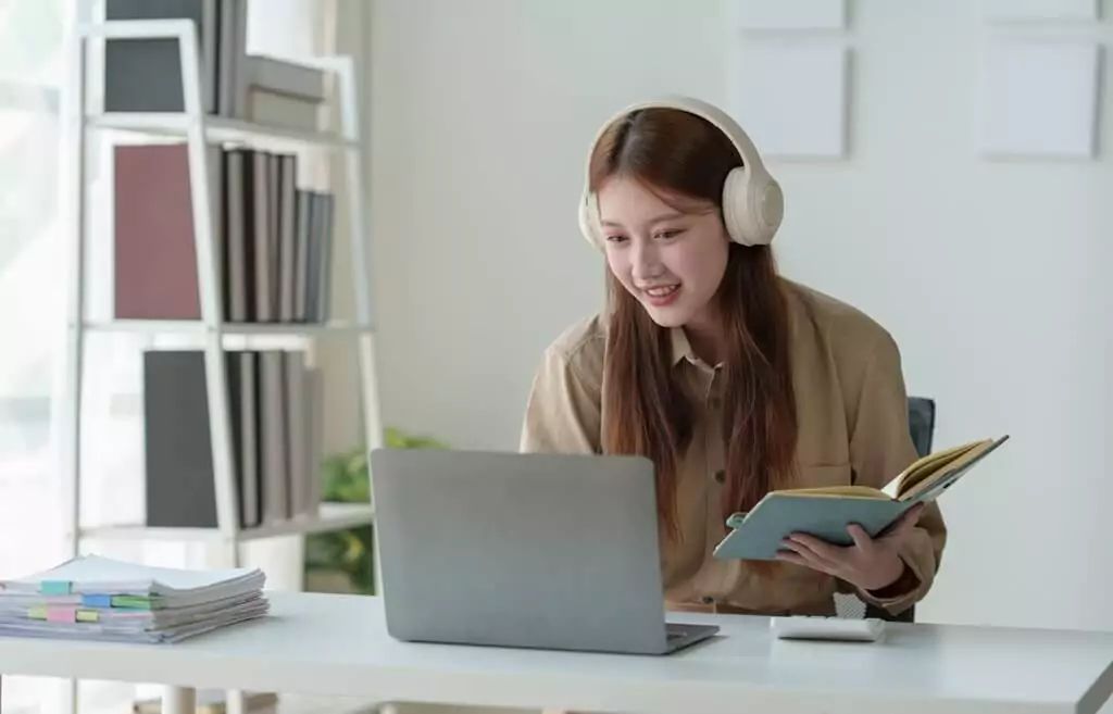 moça estudando com livro e computador