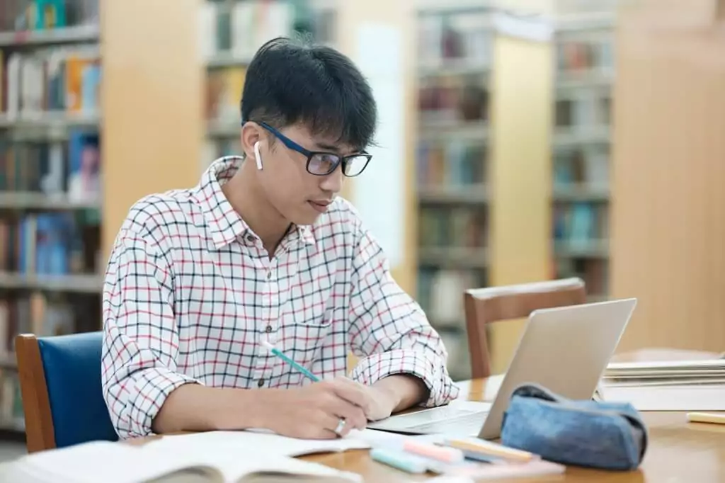 rapaz estudando em biblioteca