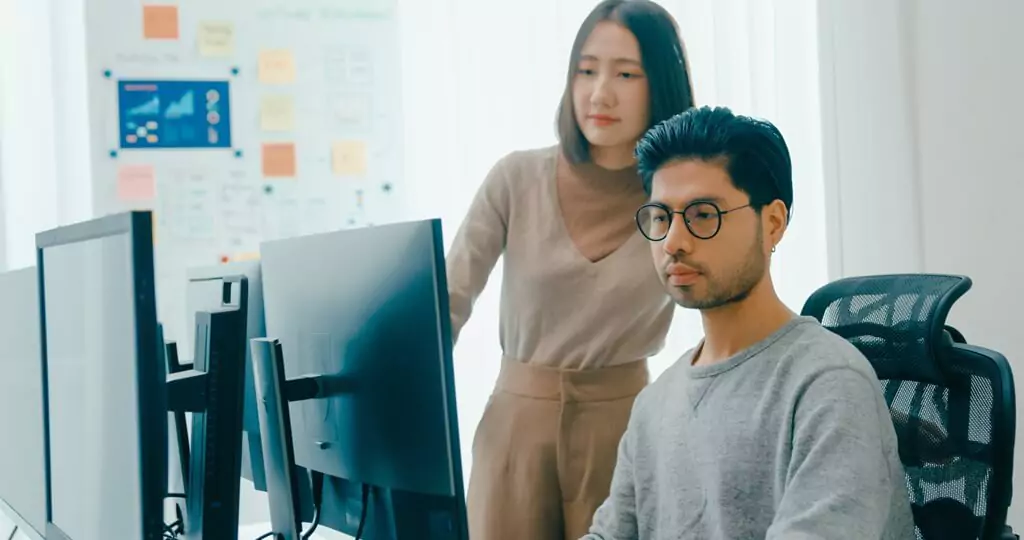 homem e moça analisando algo em computador em empresa