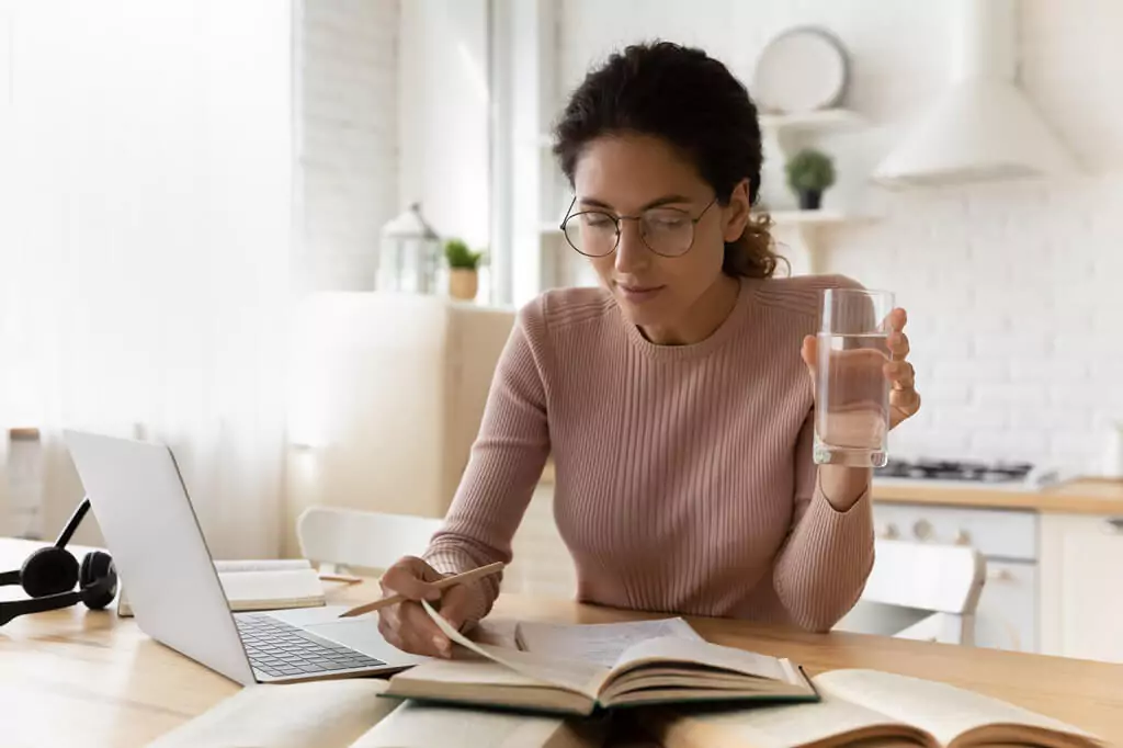 moça estudando com livro e computador