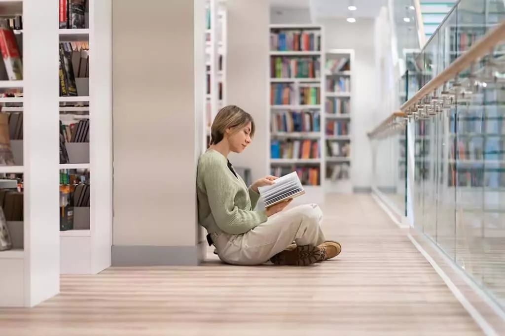 moça sentada no chão de biblioteca