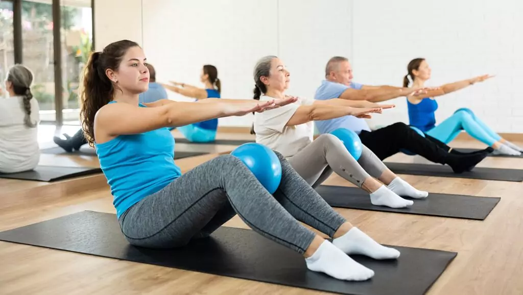 moça se exercitando com outras pessoas na aula de pilates