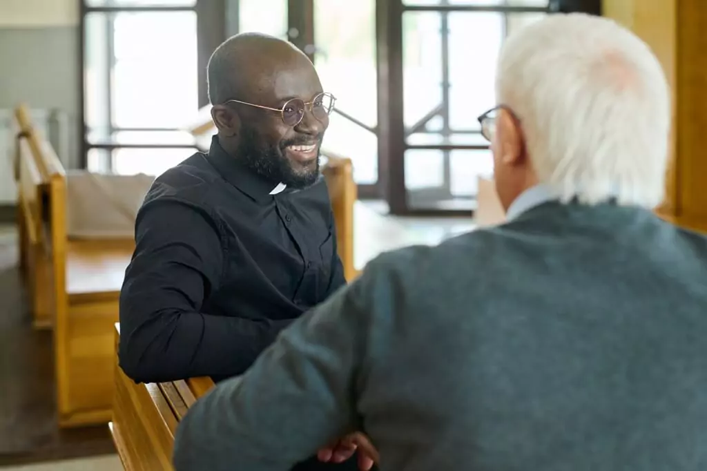 padre conversando com idoso em igreja