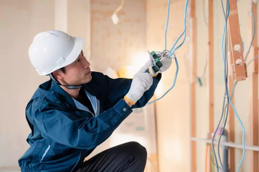 homem mexendo em instalação elétrica de construção