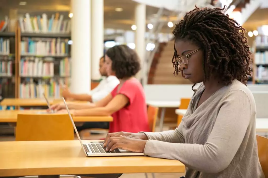 moça com computador em biblioteca