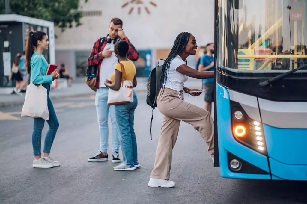 moça entrando em ônibus e estudantes ao lado