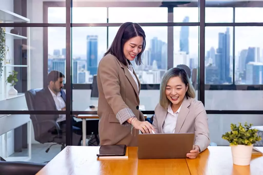 mulher orientando moça em trabalho em computador