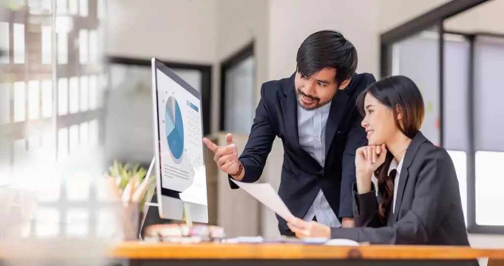 homem e mulher analisando gráfico em computador