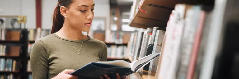 moça lendo livro em biblioteca